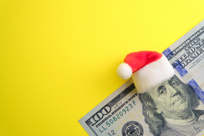 Santa hat on Benjamin Franklin on $100 bill on yellow background