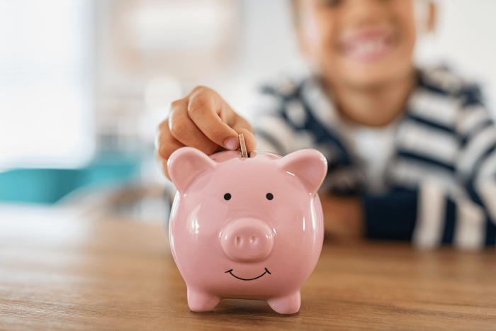 child putting coin into piggy bank