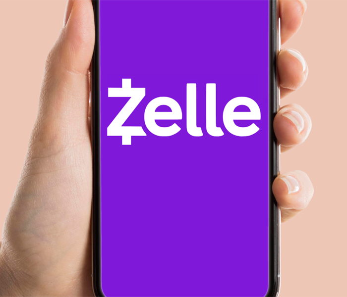 Hand holding phone with Zelle logo on screen