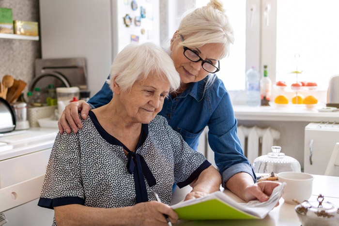 Older women at kitchen table looking over paperwork