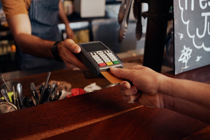 Hand placing bank card into a merchant payment machine at a restaurant