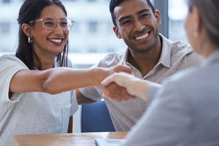 Couple sitting in an office meeting with business woman and shaking hands