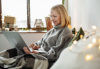 Woman at home using laptop wrapped in blanket